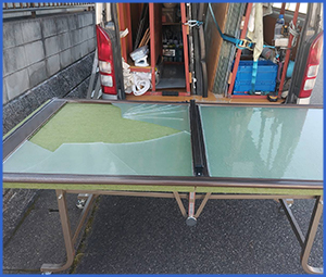 大きく破損したガラスをテーブルに置いた画像