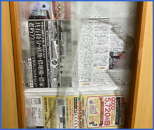 新聞紙の上に割れたガラスが置かれている画像