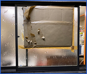 ガラスが割れたため段ボールで補強してある窓の画像