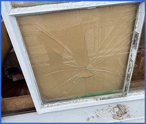 放射状に割れた窓ガラスに段ボールを当てている画像