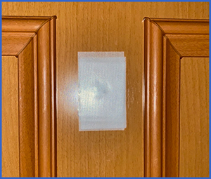白い養生テープが貼られている木製ドア画像