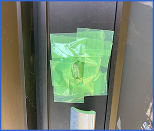 緑の養生テープが貼られた玄関の鍵穴の画像