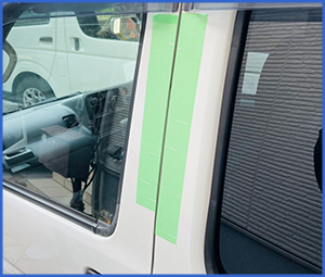 白い車体の車のドアに緑の養生テープが貼られている画像